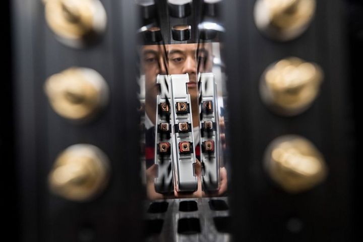 An employee installs a Lithium-ion battery cell into a testing system